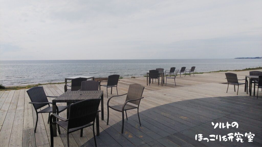 広大な海を目の前にくつろぐことができる、能登千里浜レストハウス内にあるカフェのテラス席の写真。